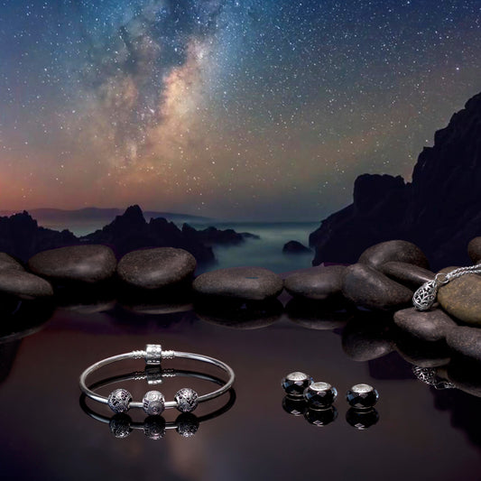 Evolve Nightfall Jewelry set on stones with a starry night sky background