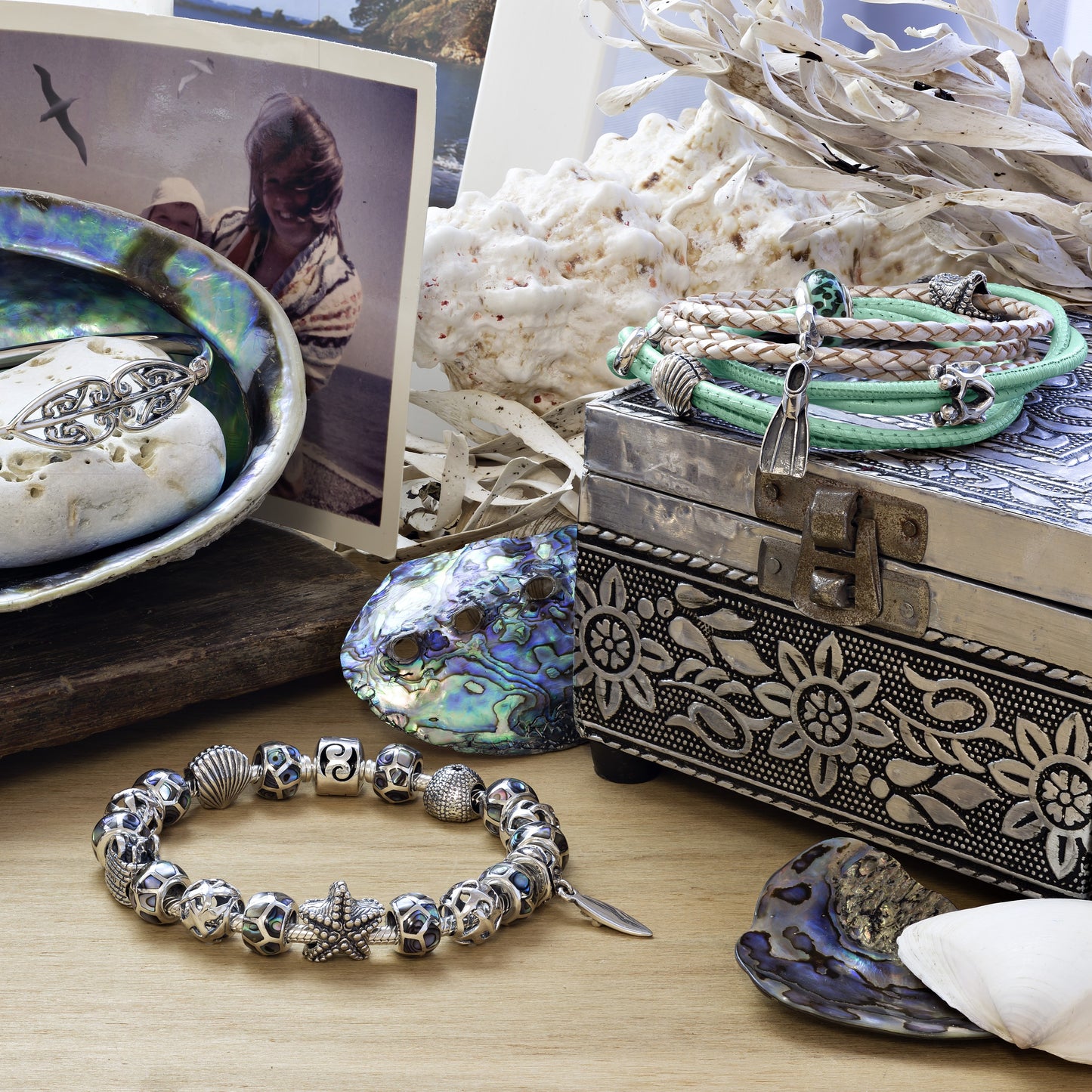 Silver bracelet with charms on a wooden surface with decorative items.