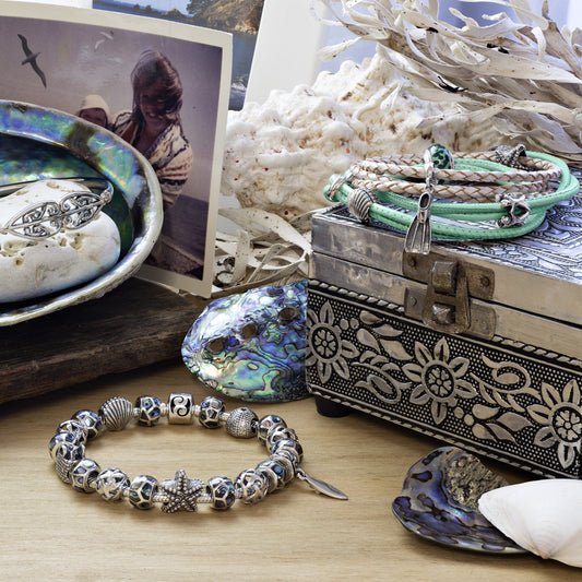 Silver bracelet with charms on a wooden surface with decorative items.